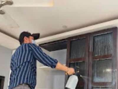 Technician spraying wardrobe joints during bed bug treatment in a flat