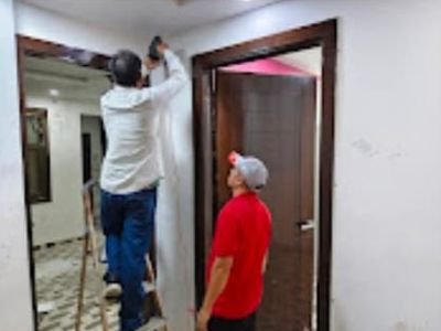 Two technicians inspecting a wooden door frame for wood borer and termites