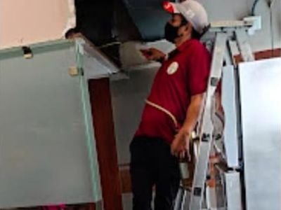 Technician on a ladder inspecting a restaurant kitchen for pests